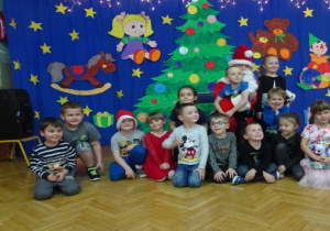 Na tle dekoracji dzieci pozują do zdjęcia z Mikołajem.